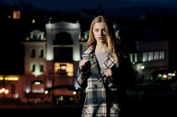 Fototapeta na wymiar night city with girl, blonde young model in black coat