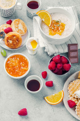 Morning atmosphere. Healthy breakfast with porridge, oatmeal, pancakes, lots of berries and snacks on blue rustic background.