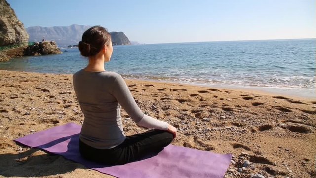 Young asian woman practicing yoga on a beach in winter