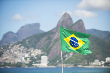 Brazilian flag flying in front of the Rio de Janeiro, Brazil city skyline with Two Brothers Mountain at Ipanema Beach