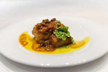 Monkfish with red sauce and broad ben in a dish.