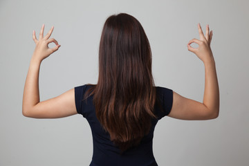 Back view of Asian woman show double OK hand sign.