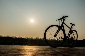 Fototapeta na wymiar silhouette of bicycle near lake and Sunset on beautiful sky