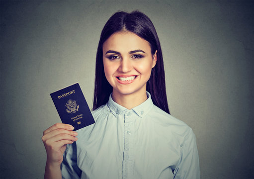 Portrait attractive young happy woman with USA passport isolated on gray wall background. Positive human emotions face expression. Immigration travel concept