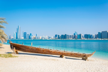 Wooden boat at the Heritage Village, in front of the Abu Dhabi skyline, United Arab Emirates