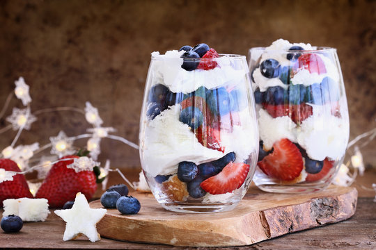 Trifle made with blueberries, strawberries, whipped cream and star shaped pound cake against a rustic background. Perfect for fourth of July. Shallow depth of field with selective focus.