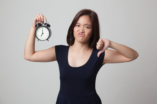 Young Asian woman thumbs down with a clock.