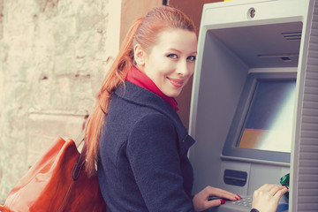 Young happy woman using ATM