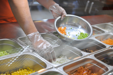 the cook puts pieces of vegetables for salad in a bowl. tray with assorted for salad in the window of a fast food restaurant © warloka79