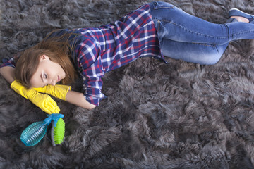 
Tired young woman  sleep  on  carpet  after cleaning home 
