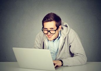 Young sly devious man using a laptop plotting server sabotage - obrazy, fototapety, plakaty