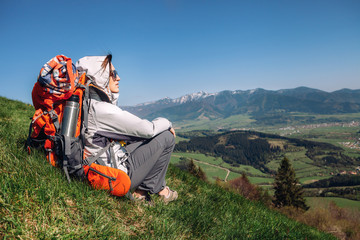 Fototapeta na wymiar Woman backpacker traveler sitis on the mountain hill with beautiful view on valley