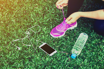 Female runner with smartphone and water bottle on grass