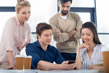group of young business people using smartphone on small business meeting