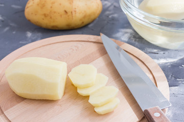 Cooking potato chips. Slicing potato on woooden board. Preparing food. Healthy vegetarian food