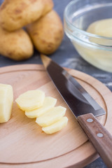 Fototapeta na wymiar Cooking potato chips. Slicing potato on woooden board. Preparing food. Healthy vegetarian food