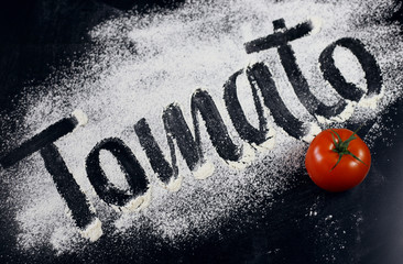 The inscription on the flour. Tomato. Black background