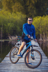man cyclist Rides on a wooden bridge across the river