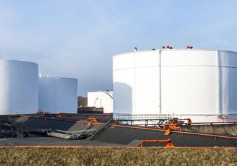white tanks in tank farm with blue sky
