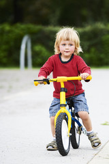 Happy toddler boy riding bike. Kids enjoying a bicycle ride. Sport concept. First bike for little child. Active toddler kid playing and cycling outdoors.