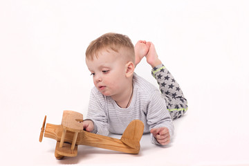 The boy is playing with a wooden plane. Isolated background