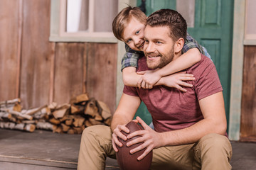 young father with little son sitting on porch at backyard, dad and son playing