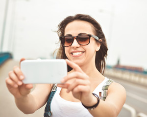 Beautiful young brunette with long hair taking a selfie in an urban context