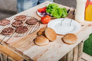close up view of various burgers ingredients on wooden table