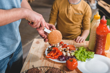 partial view of dad and son cooking meat burgers together