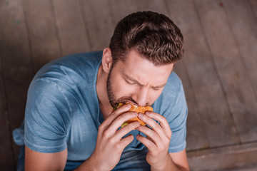 high angle view of young man eating burger