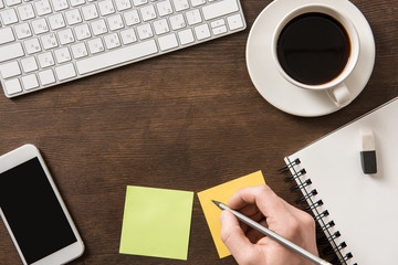 top view of man writing on sticker on home office table