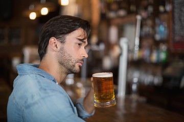 Man looking away while drink beer at pub