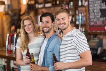 Happy friends holding beer bottles at pub
