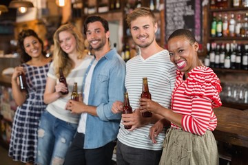 Obraz premium Cheerful friends with beer bottles at pub