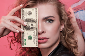 portrait of woman covering face with dollar isolated on pink