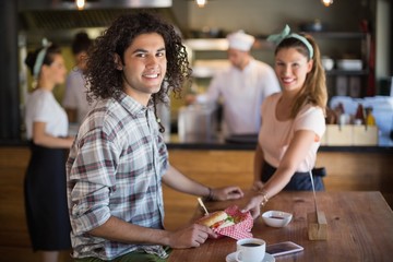Waitress serving burger to young man in restaurant