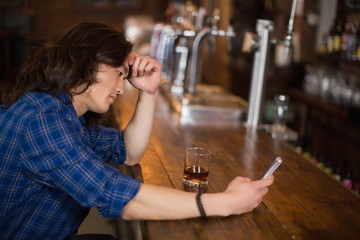 Depressed young man using mobile at pub