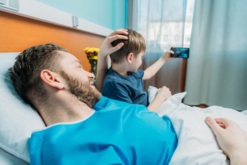 Obraz na płótnie Canvas young father and son taking selfie on smartphone at ward, dad and son