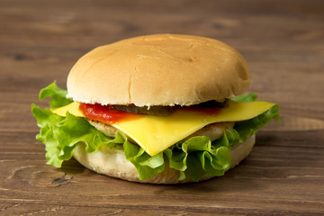 Tasty burger with cheese isolated on wooden background