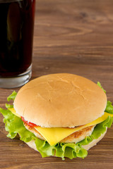 Cheeseburger and glass of on wooden surface