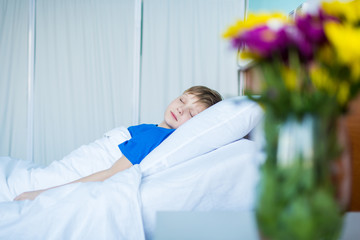 Cute little sick boy sleeping in hospital bed