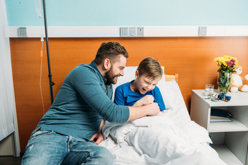 smiling dad and little son having fun in hospital chamber