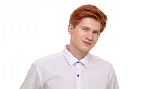 Handsome young Caucasian man with red hair seductively looking at camera flirting on white background