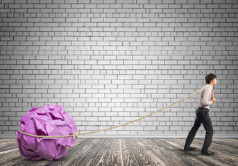 Man pulling with effort big crumpled ball of paper as creativity sign