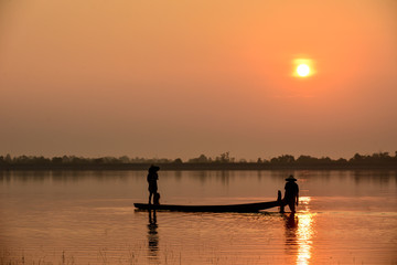 Naklejka na ściany i meble Men fishing on Silhouette a fishing boat in the River at sun rise