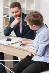 Businessman with his son drawing on business papers at office