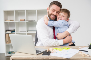 Businessman hugging with son at office