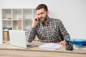 Casual businessman talking on phone at modern office