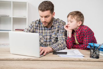 Businessman freelancer using laptop with son at home office