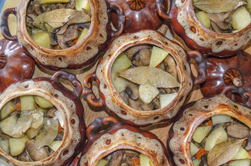 Appetizing potatoes with mushrooms baked in ceramic pots
